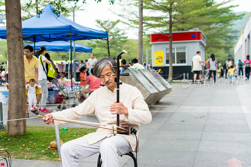 中年中国街头音乐家在中国深圳中央公园演奏中国传统乐器-二胡(中国小提琴)