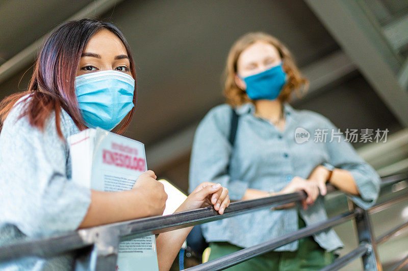 两名Z代女大学生戴着口罩站在楼梯上扶着栏杆