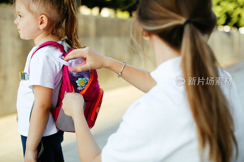 母亲在房子前为孩子准备上学