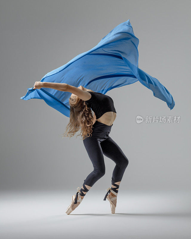 灰色背景下蓝色布料的芭蕾舞演员