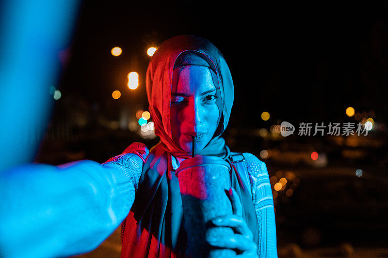 年轻的穆斯林女子在晚上喝着零浪费咖啡的时候自拍