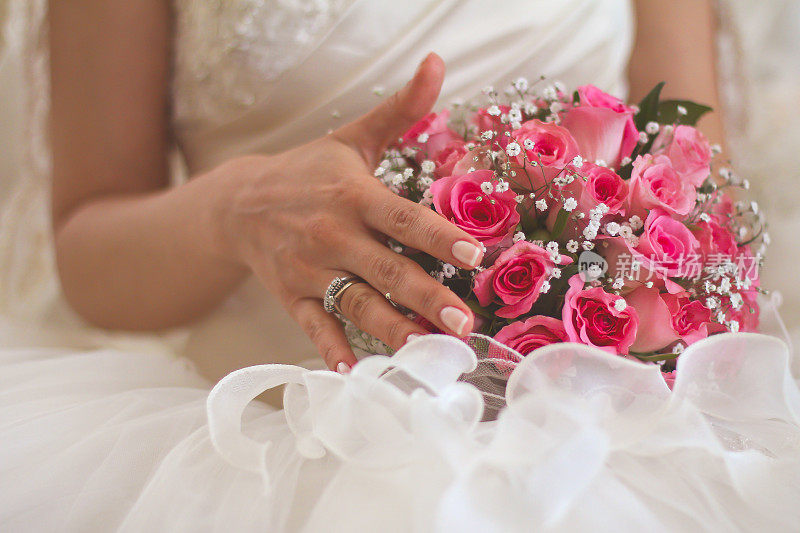 新娘拿着一束粉红色的玫瑰