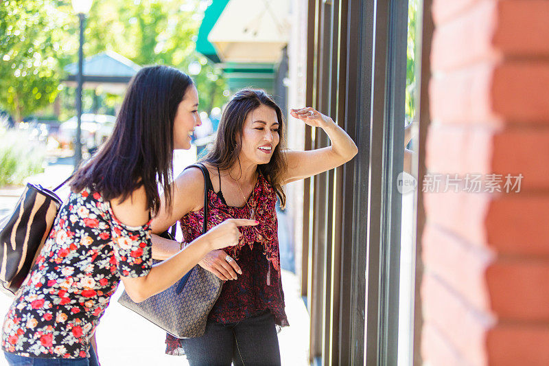 两个女人在城市街道上橱窗购物
