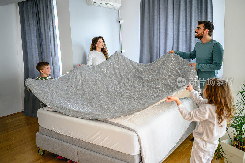 快乐的一家人一起铺床，一起玩乐。