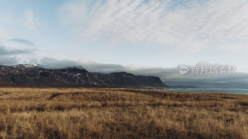 壮观的日落在美丽的冰岛的山脉和海岸线上