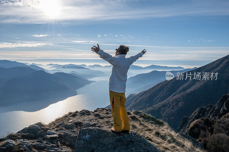 一个徒步旅行者双臂伸开站在山顶上