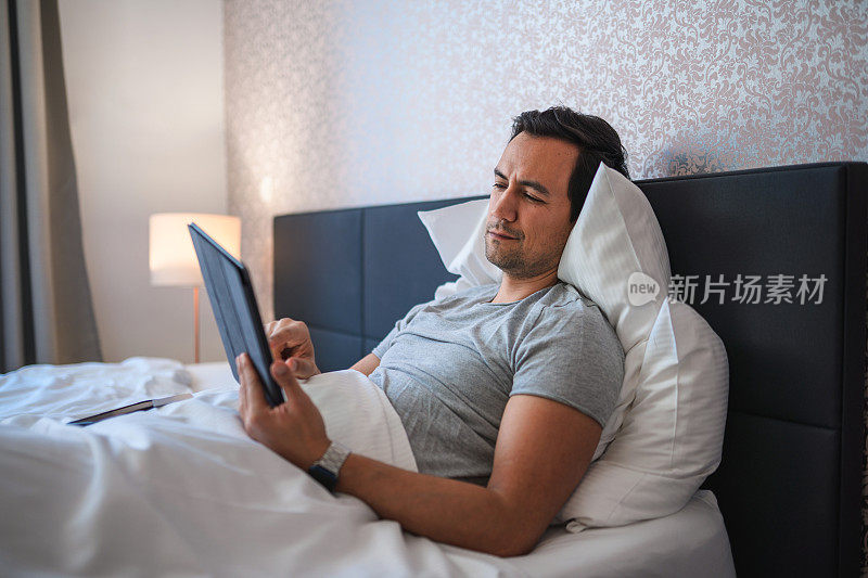 日本中年男性在卧室里使用数字平板电脑和网上购物
