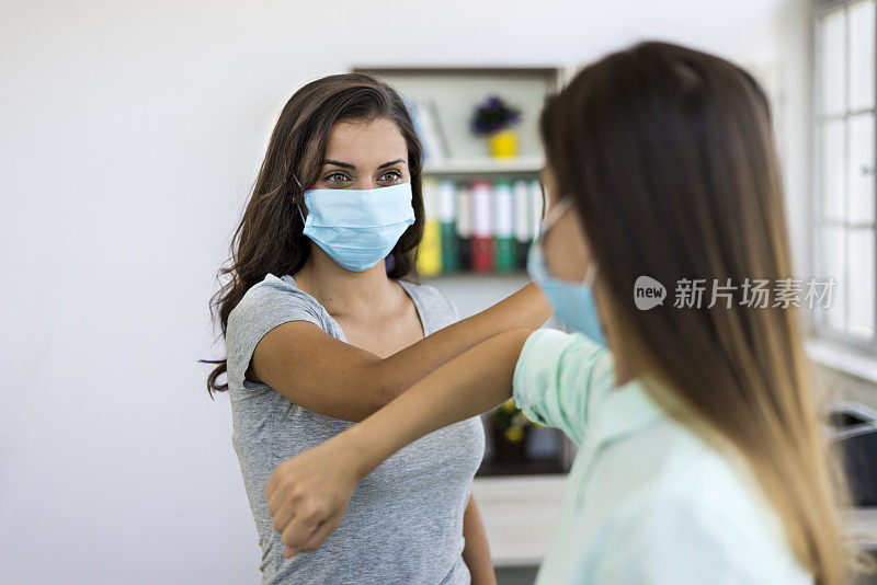 在新冠肺炎大流行期间，两名女性在办公室佩戴防护口罩