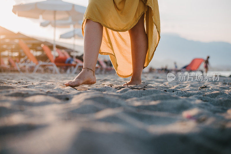 女人踩着潮湿的沙子和海水