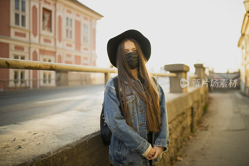 在冠状病毒大流行期间，年轻妇女在户外佩戴黑色防护口罩的肖像