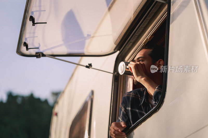 英俊的年轻亚洲男子，在公路旅行，坐在露营车里在早上。舒适的设置在露营拖车或货车。21、千禧年旅行潮流，冒险路上行