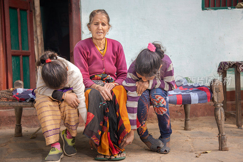 印度母亲和女儿一起坐在村里的传统床上
