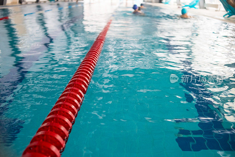 比赛池的泳道。蓝色水上红色塑料绳道室内游泳池运动比赛背景。有选择性的重点。