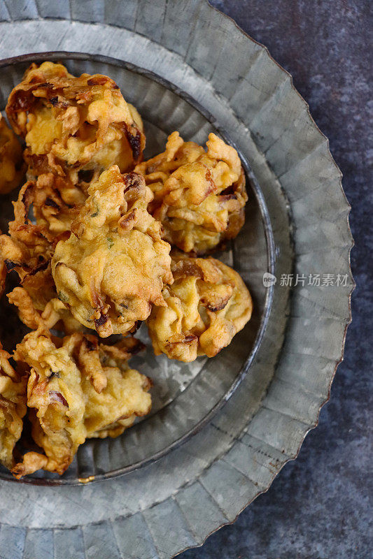 特写图像的托盘与有图案的盘子自制脆洋葱bhajis，印度美食素食小吃，灰色背景，高架视图