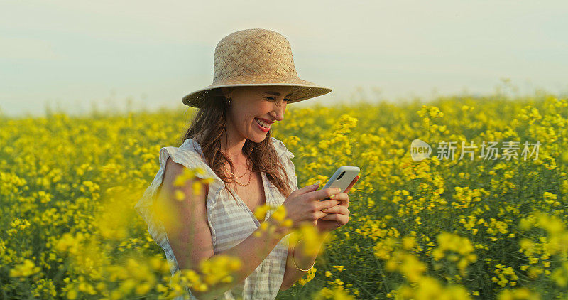 一名年轻女子在花丛中使用智能手机的照片