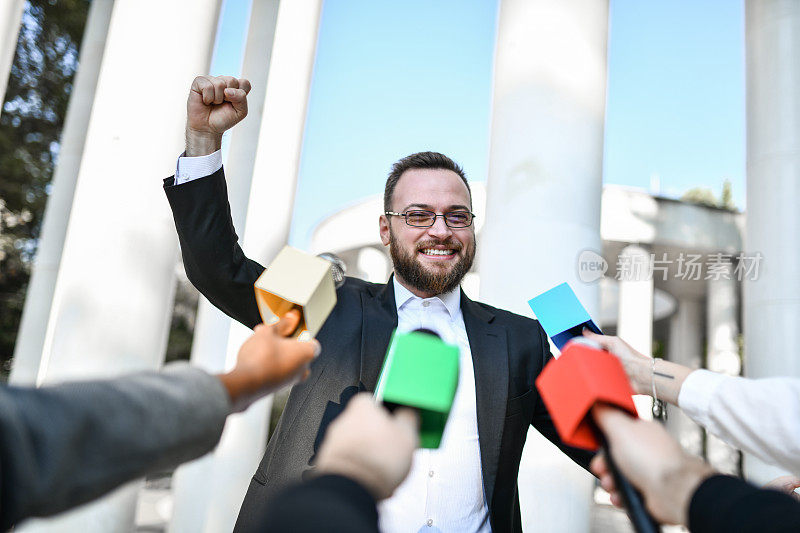 英俊的男性政治家在新闻发布会上为自己的竞选欢呼
