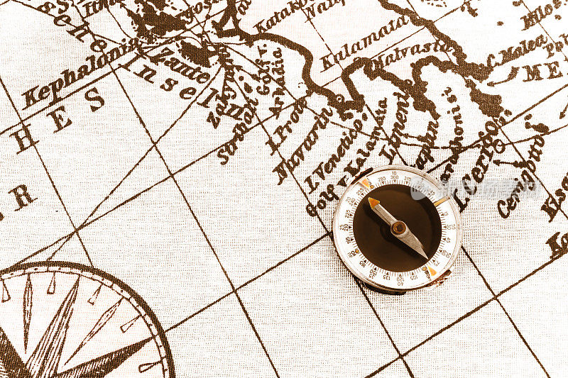 世界古董地图上的磁性旧指南针。旅游、地理、航海、旅游和探险概念背景。微距拍摄，浅聚焦。