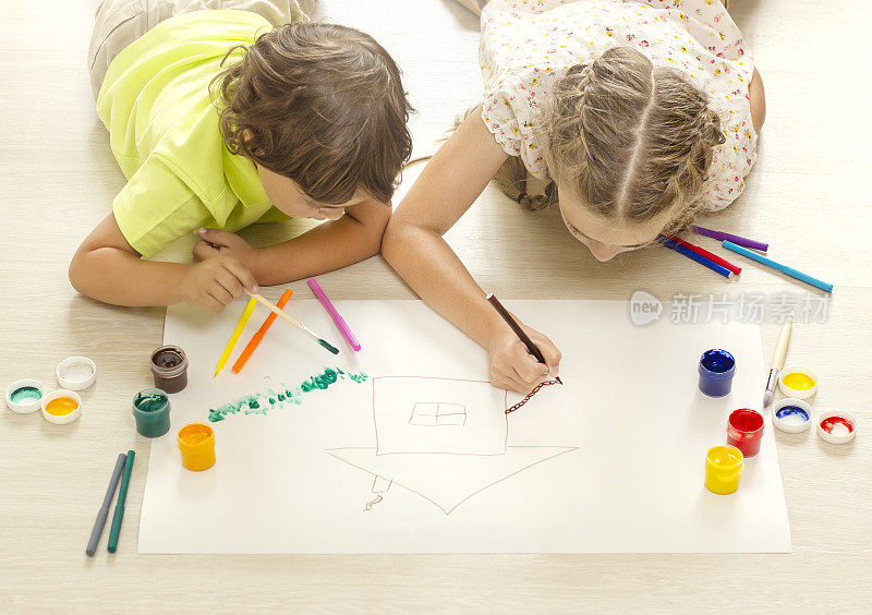 孩子们躺在地板上用颜料画画。