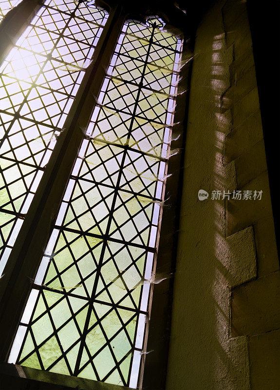 教堂窗户上布满了阳光照耀下的蜘蛛网