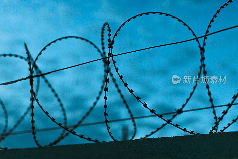 铁丝网映衬着黄昏的天空。《暮光之城》。监狱的概念。自由。