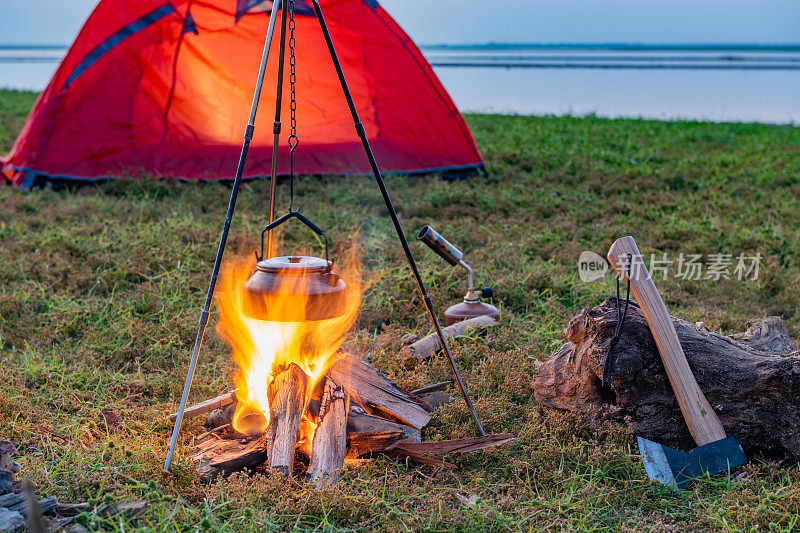 在湖边草地上的橙色帐篷里营火