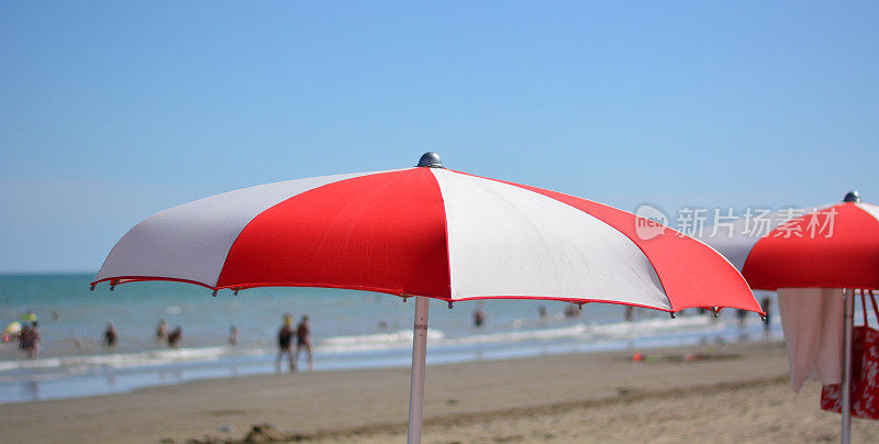 一把红白相间的伞挡在海浪前