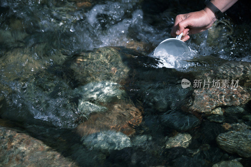 一位女背包客正在山河中取水