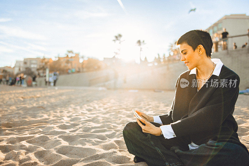 一名年轻女子在城市海滩上用她的数码平板电脑观看溪流