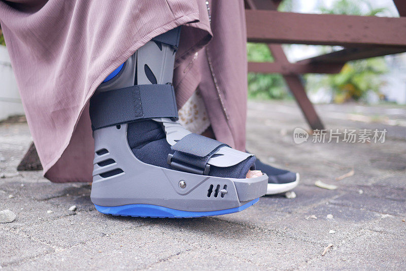 女性骨折的脚与灰色塑料靴踝关节护具受伤保护靴