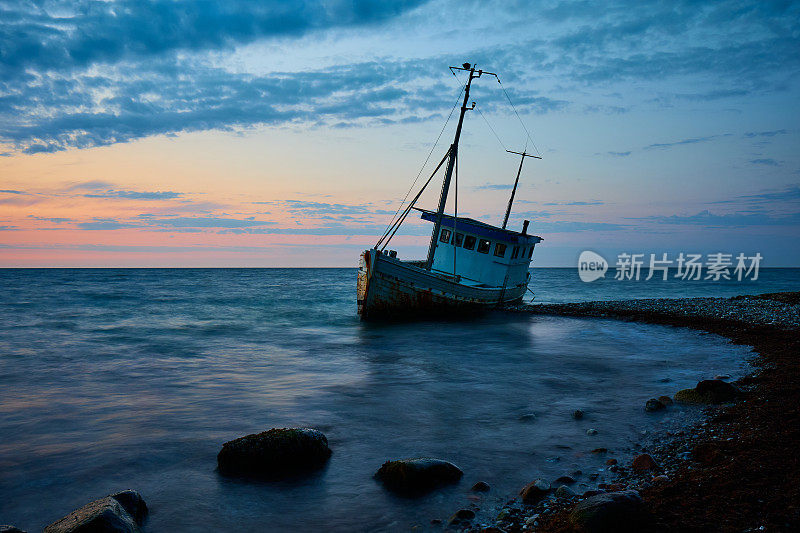 落日时，海岸线上的海上被遗弃的船只映衬着天空