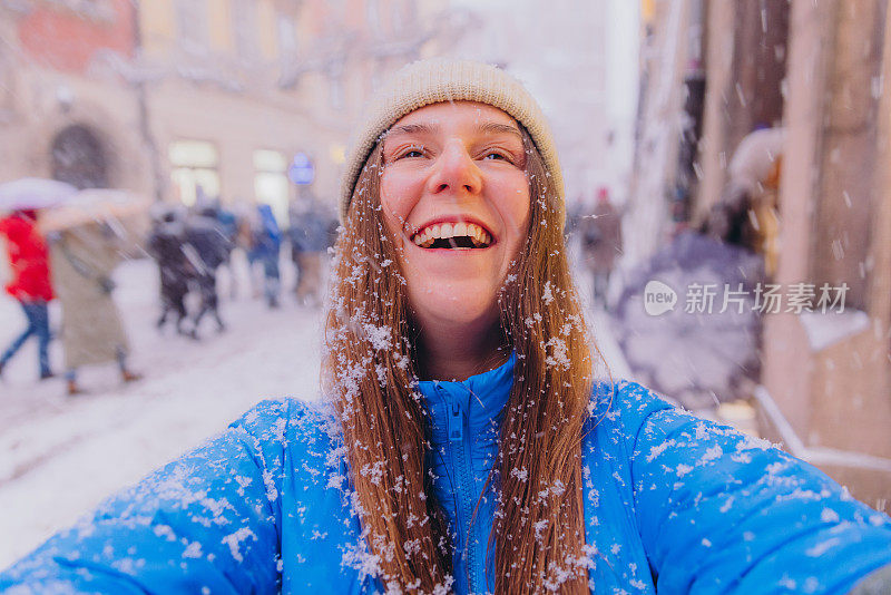 快乐的女性影响者在克拉科夫拍摄自拍，思考下雪的圣诞节