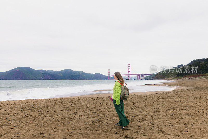 背着背包的女人在加利福尼亚旧金山的贝克海滩沉思