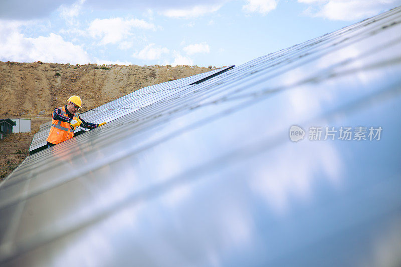 太阳能电池板安装:技术人员在工厂屋顶上与钻机一起工作