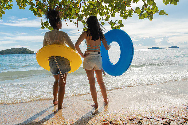 两名年轻女子正准备在海滩上拿着内胎玩海