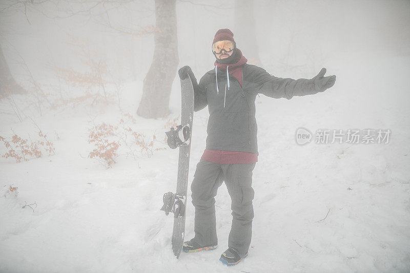 在雾蒙蒙的冬日，一名男性滑雪板运动员准备在山上滑雪