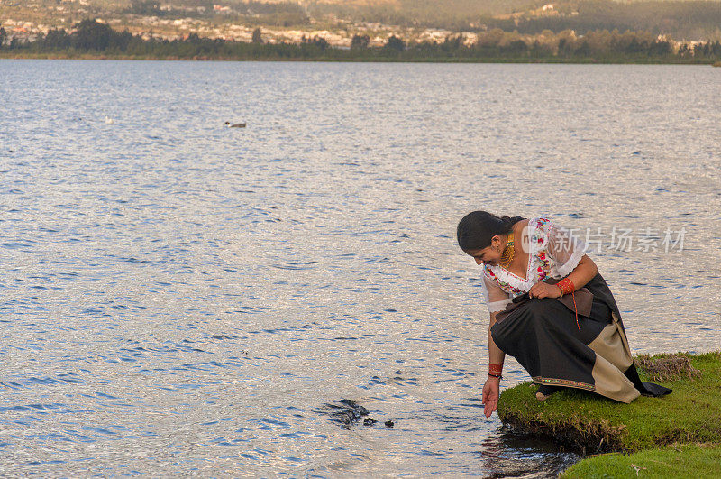 一位土著妇女站在泻湖边，用手抚摸着湖水