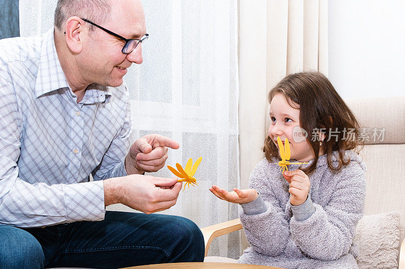 一个白人男子和一个7岁的女孩，用木制材料制作蜻蜓玩具。
