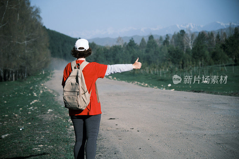 女背包客在山路上搭车