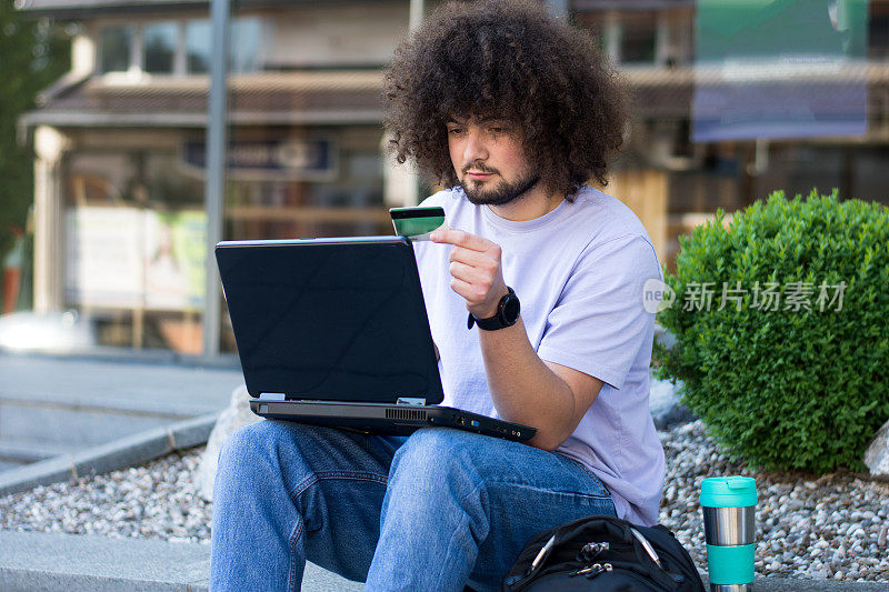 男子使用笔记本电脑和信用卡进行网上购物