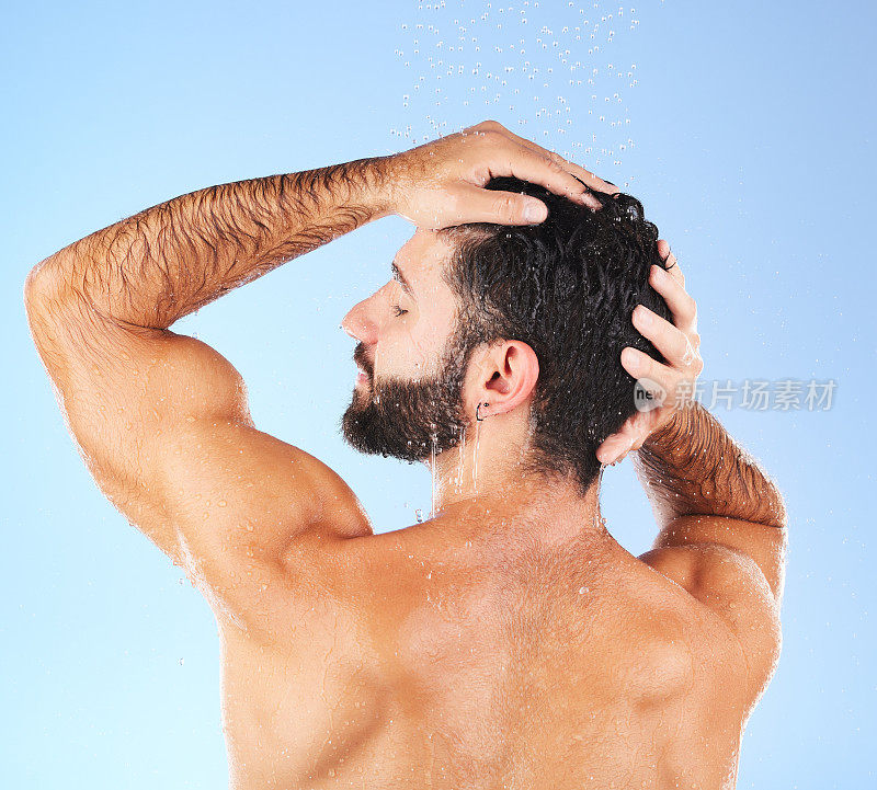 头发护理，淋浴和男士模型在水清洁，皮肤护理和卫生保健。隔离，蓝色背景和工作室，一个年轻人在浴室进行皮肤病学和自我护理