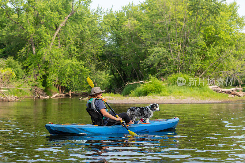 女孩和狗在夏天沿着朗姆河划皮划艇