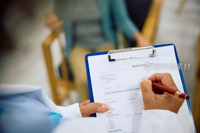 女医生在诊所候诊室填写病人的医疗文件的特写。