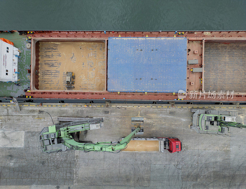 在港口仓库使用门式起重机进行装货作业。粮食从货船转运到卡车货舱