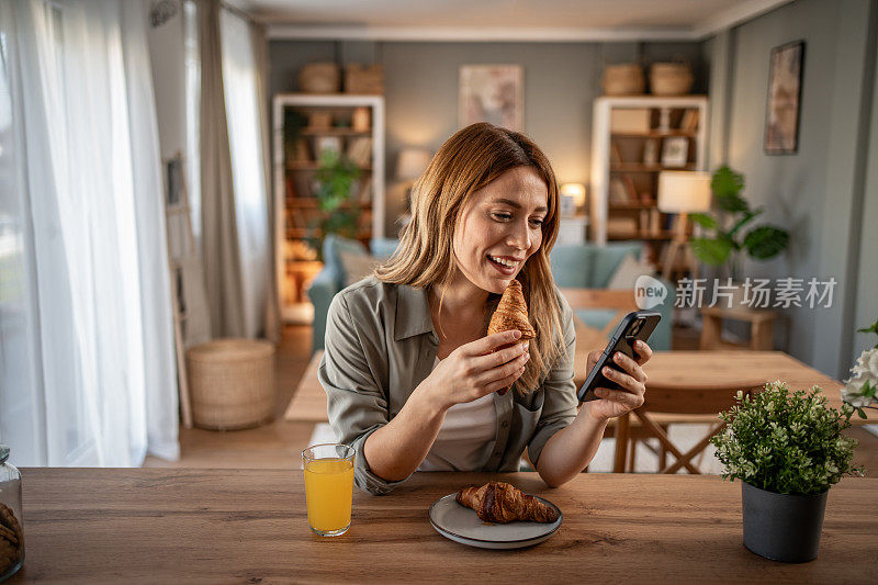 年轻漂亮的女人在家里吃牛角面包和黄油早餐，享受她的一天休息