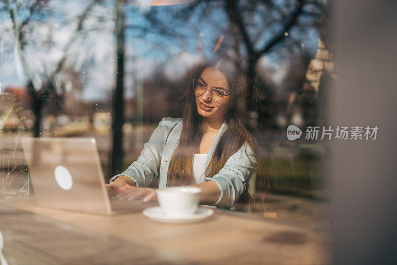 一位年轻女子在咖啡店使用她的笔记本电脑。