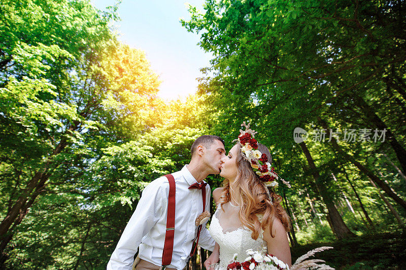 快乐的新娘和新郎漫步在夏日的森林里
