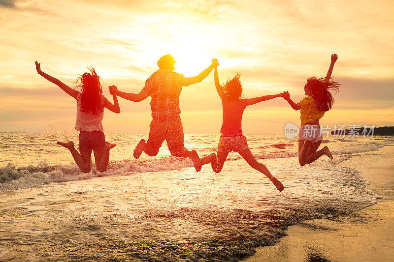 一群快乐的年轻人在海滩上蹦蹦跳跳