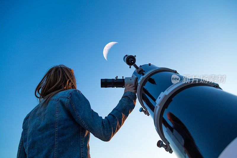 用望远镜看月亮的女孩。