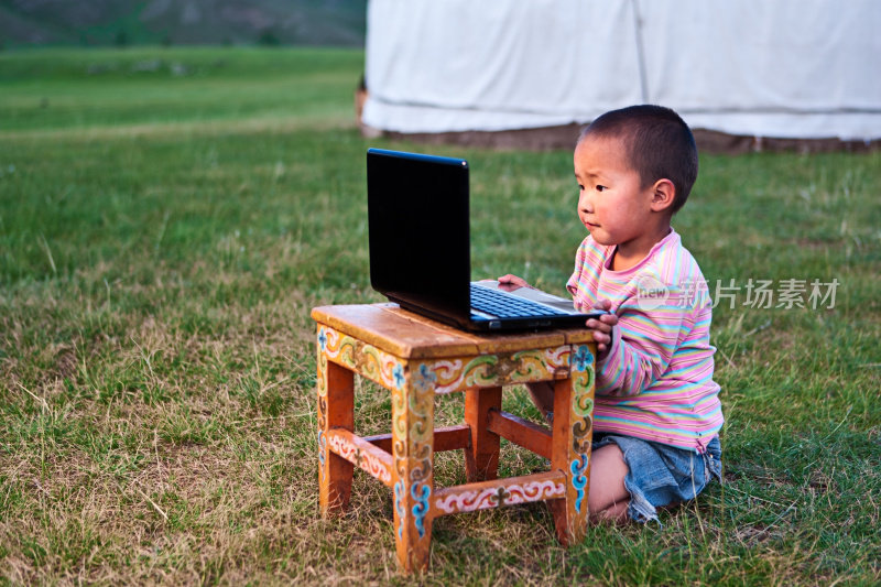 一个蒙古小男孩在用笔记本电脑