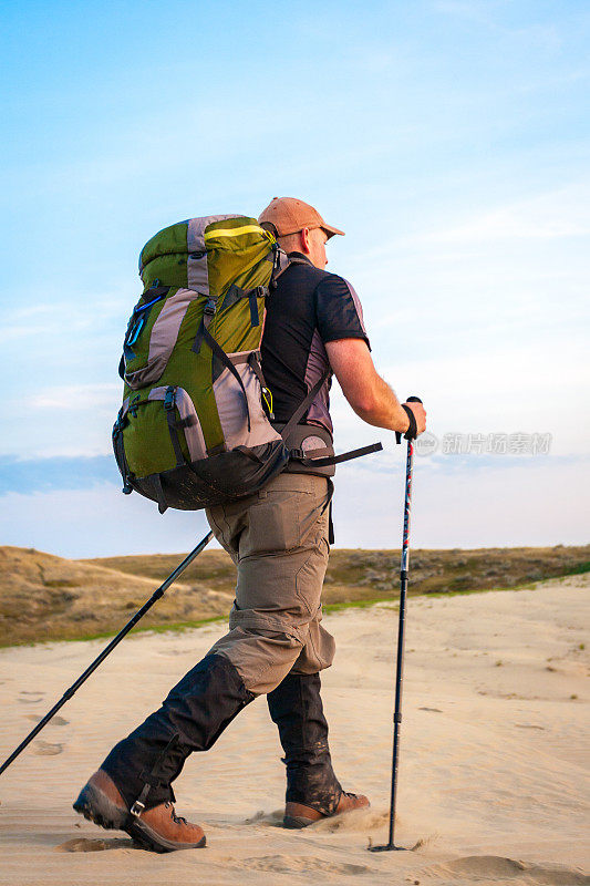 背着背包在沙漠中徒步旅行的男人
